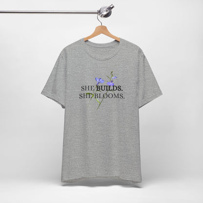 She Builds. She Blooms. - Women's Motivational Tee