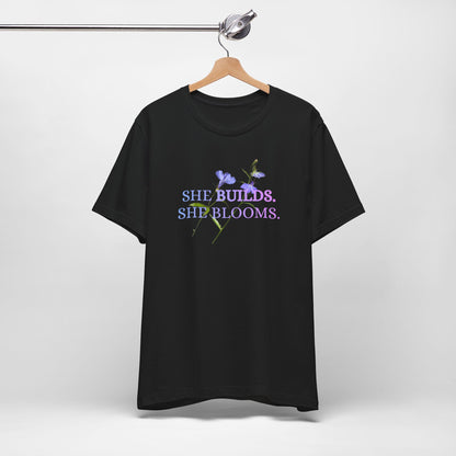 She Builds. She Blooms. - Women's Motivational Tee