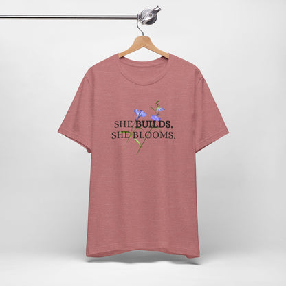 She Builds. She Blooms. - Women's Motivational Tee