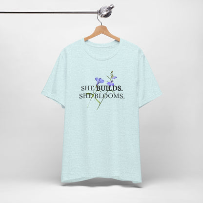 She Builds. She Blooms. - Women's Motivational Tee
