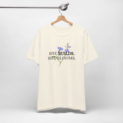 She Builds. She Blooms. - Women's Motivational Tee