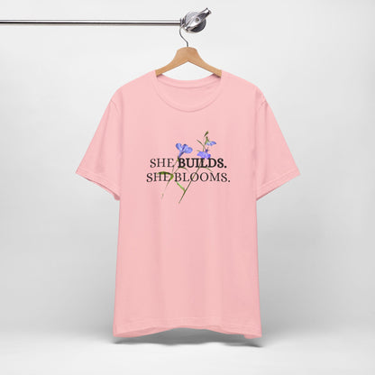 She Builds. She Blooms. - Women's Motivational Tee