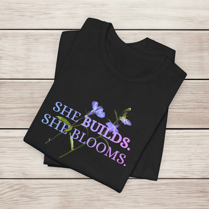 She Builds. She Blooms. - Women's Motivational Tee