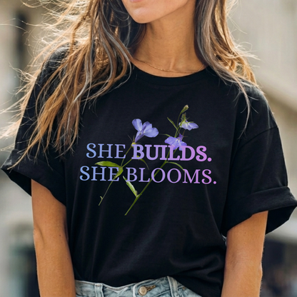 She Builds. She Blooms. - Women's Motivational Tee