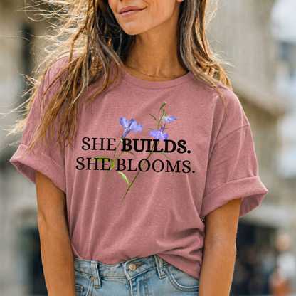 She Builds. She Blooms. - Women's Motivational Tee