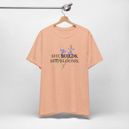 She Builds. She Blooms. - Women's Motivational Tee