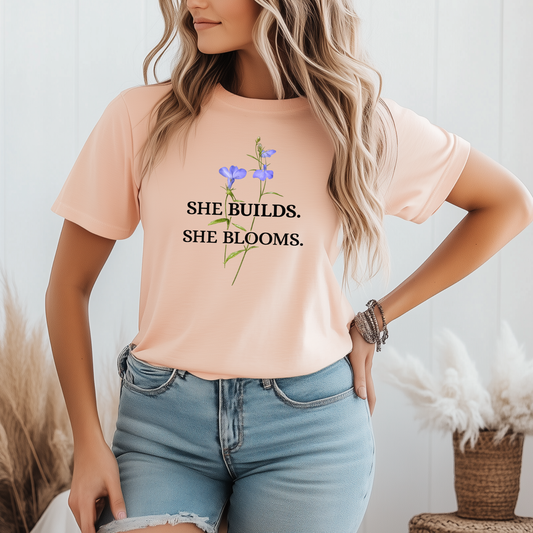 She Builds. She Blooms. - Women's Motivational Tee